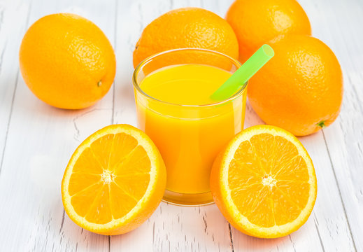 Orange juice and oranges on wooden table