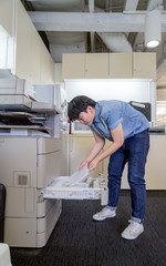 woman inserting paper in laser printer cartridge in office