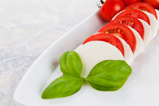Mozzarellasalat mit Tomaten und Basilikum auf einem Marmortisch