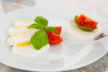 Mozzarellasalat mit Tomaten und Basilikum auf einer Gabel