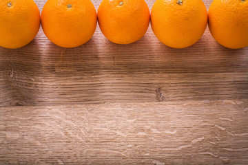 five oranges organized in row on wooden board