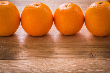 four orange fruits organized in row on wooden board