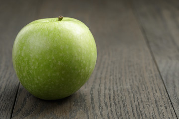 one green apple on wood table