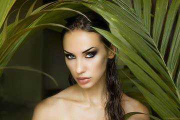 Fototapeta premium Sexy beautiful woman hiding behind the palm leaves. Beautiful st