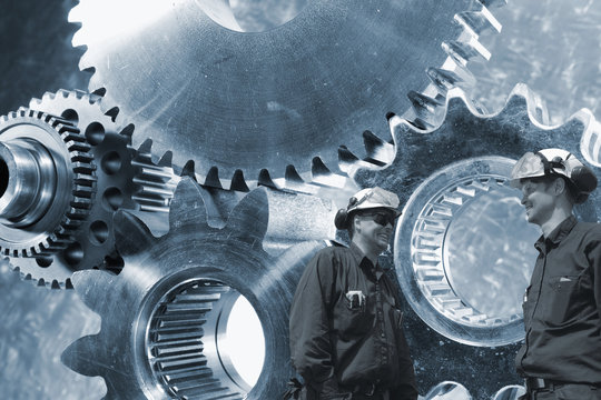 engineers working with large cogwheel machinery in background
