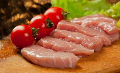 Raw pork оn the wood board. Tomato and lettice