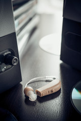 Vintage stylized photo of hearing aid and music speaker.