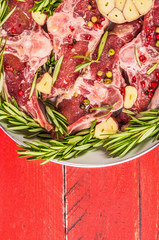 Raw lamb loin chops with rosemary and garlic in white frying pan