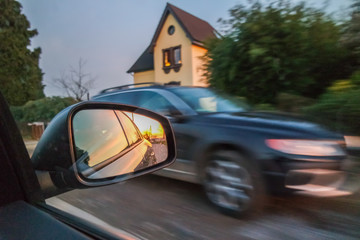 Obraz premium Sunset in a mirror with blurry car in background