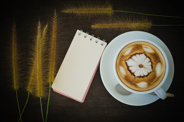 latte art coffee and notebook on wooden background