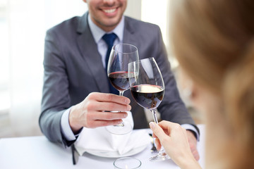 happy couple with glasses of wine at restaurant