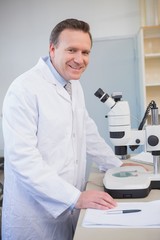 Naklejka na ściany i meble Smiling scientist examining sample with microscope