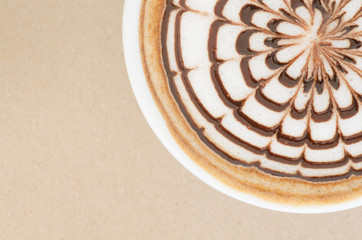 a cup of latte art on brown paper background