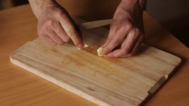 man on a kitchen board cuts garlic