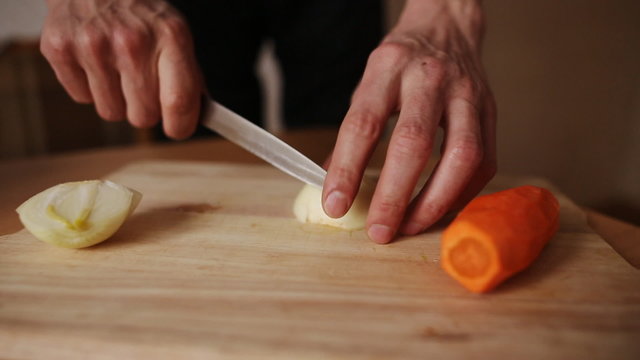 man on a kitchen board cuts onion