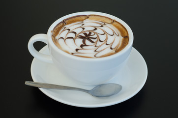 a cup of latte art on black background