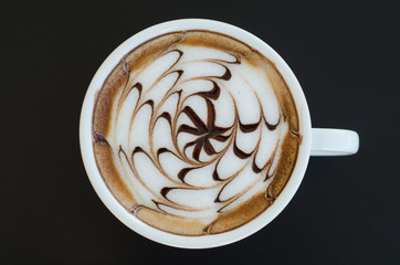a cup of latte art on black background