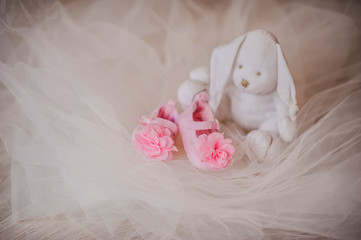 Pink booties with flowers near the white rabbit toy, decor, life