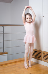 Fototapeta na wymiar Little girl practicing ballet in a dance studio