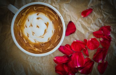 A cup of coffee with latte art and petals rose on  wrinkled pape