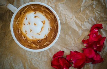 A cup of coffee with latte art and petals rose on  wrinkled pape