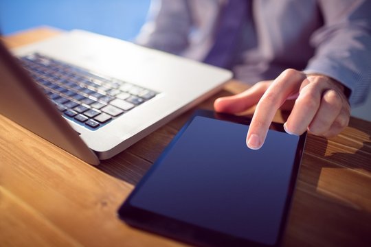 Businessman Using Laptop And Tablet At Desk