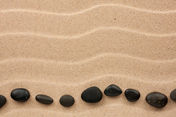 Fototapeta na wymiar Black stones lie on the sand