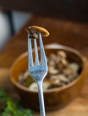 Marinated honey fungus in brown bowl on wooden table.