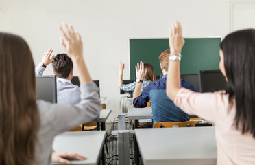 Young students raising hands in a classroom