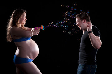 Schwangere Frau spielt mit Seifenblasen Pistole auf Mann Porträt