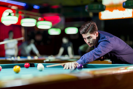 Young handsome man playing snooker