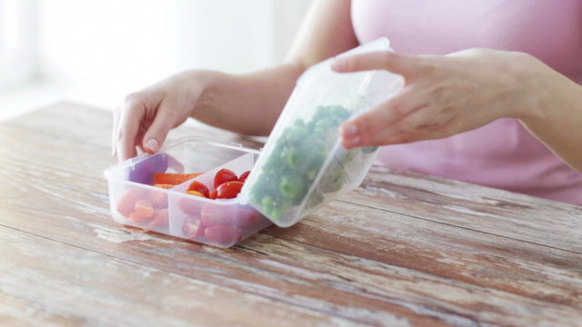 close up of woman eating vegetables from container