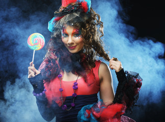 Girl with with creative make-up holds lollipop.