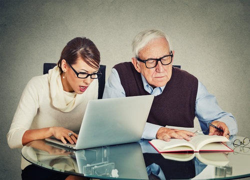 woman working on laptop and older grandpa man reading from book