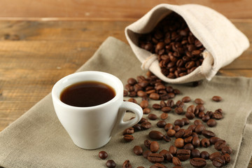 Cup of coffee with beans on rustic wooden background