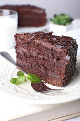 Sliced tasty chocolate cake in plate on wooden table, closeup