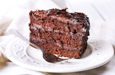 Sliced tasty chocolate cake in plate on wooden table, closeup