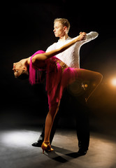 Beautiful couple of professional artists dancing on black background