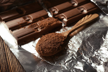 Bar of chocolate with cocoa on foil, closeup