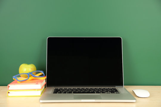 Laptop on table, on green blackboard background