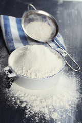 Sifting flour through sieve on wooden table, closeup