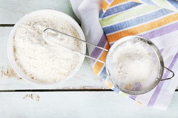 Sifting flour through sieve on wooden table, top view