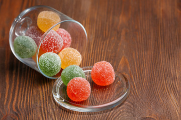 Colorful candies in jar on wooden background