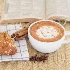 A cup of coffee with latte art and croissant on a knitted  backg