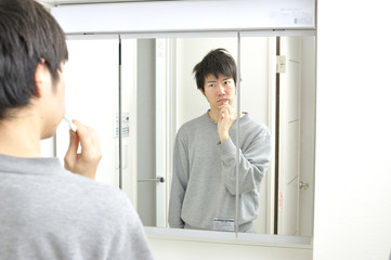 Fototapeta premium 朝起きて洗面所の鏡の前で歯を磨く日本人男性