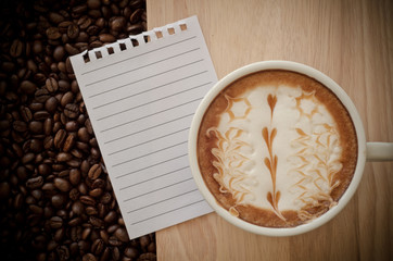 a cup of latte art on wooden and coffee bean background