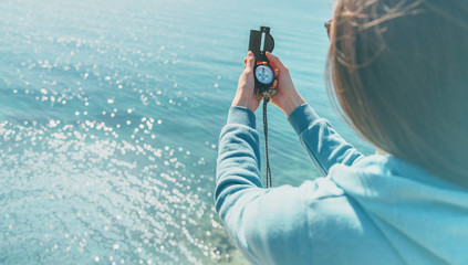 Traveler woman holding a compass on coast