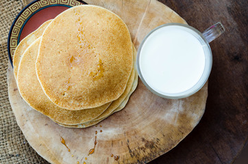 Several yellow crepes with cup of milk