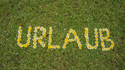 Wort URLAUB aus Blüten im Gras