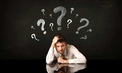 Sitting businessman under question marks